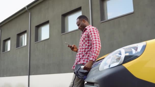 Hombre Negro Sosteniendo Teléfono Inteligente Mientras Carga Coche Del Camión — Vídeo de stock