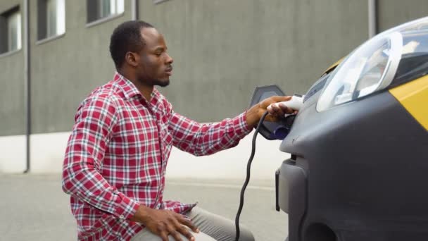 Чорний Чоловік Підключає Зарядний Кабель Вантажного Електромобіля Заряджає Батареї — стокове відео