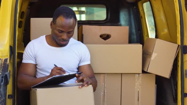 Африканский Американец Симпатичный Курьер Желтом Фургоне Коробками Заполняющими Документы Планшете — стоковое видео