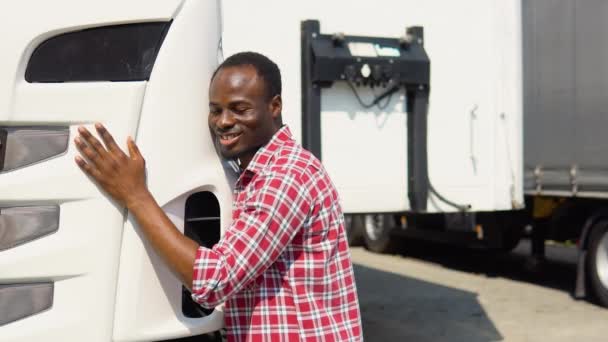 黑人卡车司机拥抱着他的卡车进行运输 快乐的非洲卡车司机热爱他的工作 — 图库视频影像