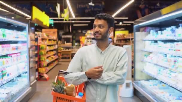 在超级市场 一个带着他的购物车走在过道上的印度男人笑着 — 图库视频影像