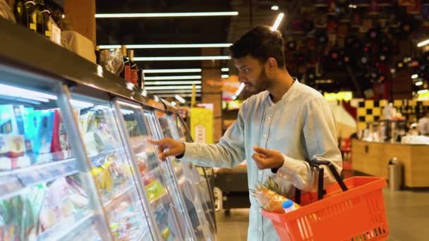 从侧面看英俊的印度男人在买奶酪 一个男人在杂货店买奶酪 — 图库视频影像