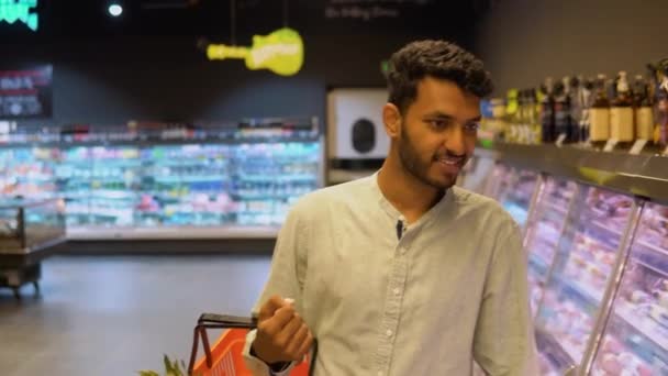 スーパーマーケットでトロリーと通路を歩いているインド人男性 食料品店で買い物をする若者 — ストック動画