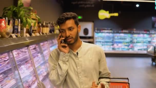Indiase Man Een Supermarkt Doet Aankopen Kiest Producten Praat Telefonisch — Stockvideo
