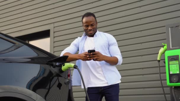 Siyah Adam Elektrikli Bir Arabanın Aküsünü Kontrol Etmek Için Mobil — Stok video