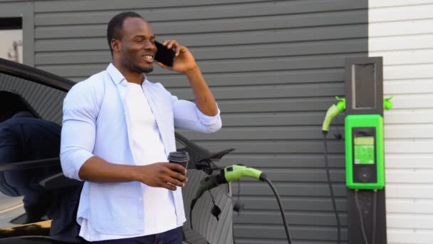 Černoch Mluví Telefonu Při Nabíjení Luxusní Elektrické Auto Stanici — Stock video