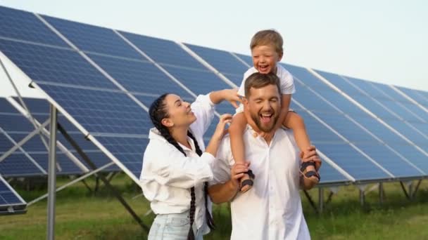3人の若い家族が太陽光パネルの近くにうずくまっていて 笑顔でカメラを見て 明るい未来の概念 — ストック動画