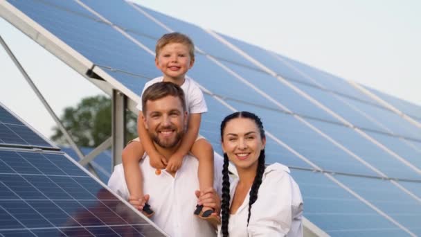 一个年轻的三口之家在光伏太阳能电池板旁休息 面带微笑地看着相机 憧憬着光明的未来 — 图库视频影像