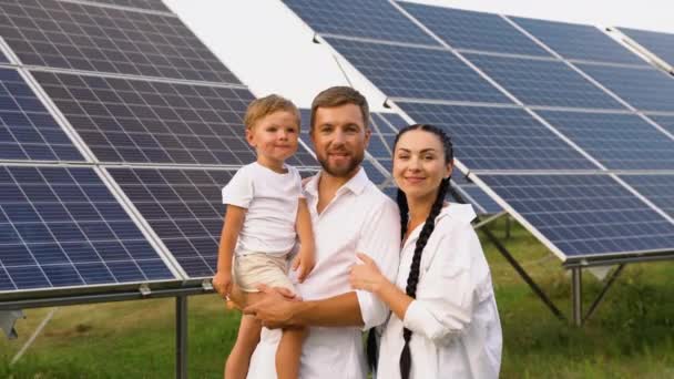 3人の若い家族が太陽光発電パネルに近づき 笑顔でカメラを見ている 明るい未来のコンセプト — ストック動画