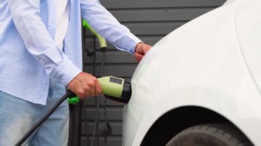 Evin yanında elektrikli araba şarj eden bir adam var..