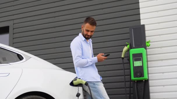 Bearded Man Smartphone Electric Car Waiting Finish Battery Charging Process — Stock Video