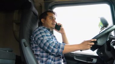 Hintli kamyoncu kamyonunda otururken telefon ediyor..