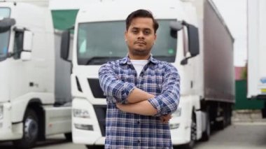 Kamyon parkında kolları çapraz duran Hintli kamyon şoförü kameraya bakıyor..