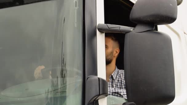 一个司机坐在半卡车里 透过开着的窗户看着摄像机 — 图库视频影像