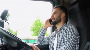 Şoför kamyonetinin kabininde otururken cep telefonuyla konuşuyor. Sağ el sürücüsü araba.