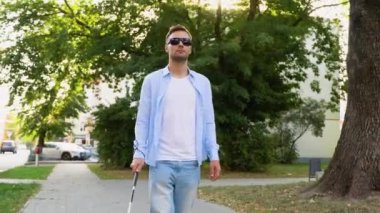 Genç kör adam bastonuyla sokakta yürüyor..