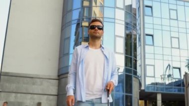 Genç kör adam bastonuyla sokakta yürüyor..