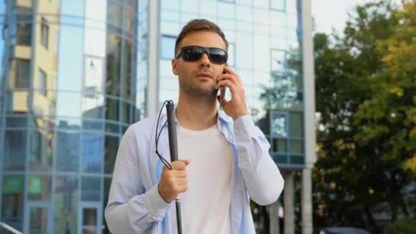 携帯電話で話す歩くスティックを持つハンサムな盲目の男 — ストック動画