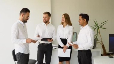 Bir grup farklı iş adamı, modern bir ofiste birlikte çalışma konusunu tartışıyor..