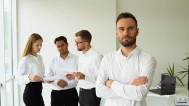 Gülümseyen olgun iş adamı lideri takım toplantısında ofiste kameraya bakıyor..