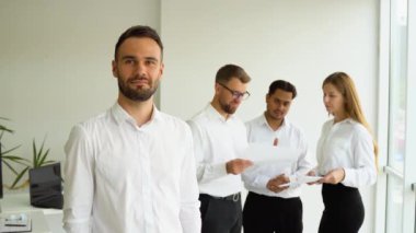 Ofisteki kendine güvenen işadamı ve arka planda duran meslektaşları.