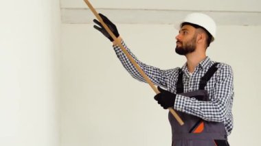 İşçi dekoratörü odada duvar boyuyor..
