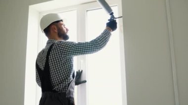 İşçi kuşak ve pencere çerçevesi arasındaki boşluğu doldurmak için poliüretan köpük uyguluyor.