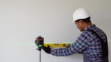 Lazer seviyesindeki aletle duvarları ölçen Hintli işçi.
