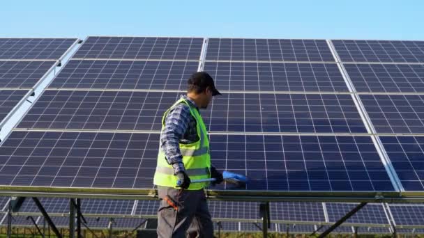 屋外の取付けの後で太陽電池パネルをきれいにするインドの労働者 — ストック動画