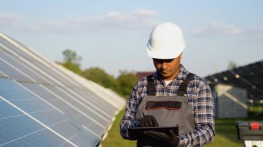 İstasyonda güneş pili panellerini koruyan dijital tablet kullanan Hintli mühendis