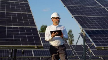 İstasyonda güneş pili panellerini muhafaza eden dijital tablet kullanan olgun 50 'li yılların mühendisi.