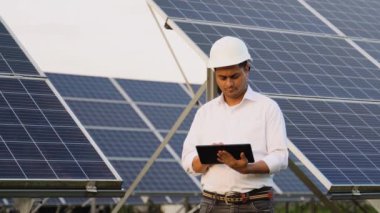 İstasyonda güneş pili panellerini koruyan dijital tablet kullanan Hintli mühendis. Alternatif ve yenilenebilir enerji kavramı