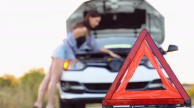 Genç kadının arabasını yol tarafında kırık aşağı yakınındaki yardım için bekler.