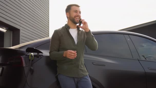 Handsome Man Phoning While Charging Car Electric Vehicle Charging Station — Stock Video