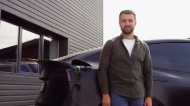 Elektrikli araba şarj ederken şarj istasyonunda bir adamın portresi..
