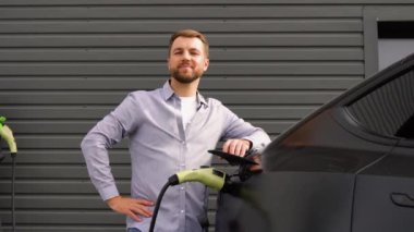 Elektrikli araba şarj ederken şarj istasyonunda bir adamın portresi..