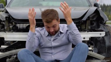 Bir adam trafik kazasından sonra stresli bir şekilde oturur. Trafik kazaları ve sigorta kavramı.
