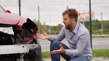 Adam araba kazasından sonra bozuk bir arabanın yanında ağlıyor.