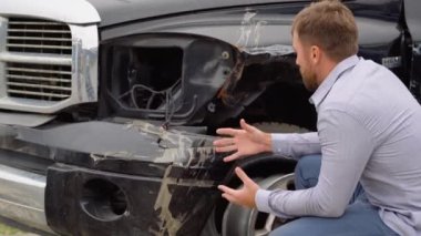 Araba kazasından sonra kaza yapmış, yolda oturan üzgün bir adamın portresi.