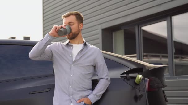 Handsome Man Charging Electric Car Drinking Coffee — Stock Video