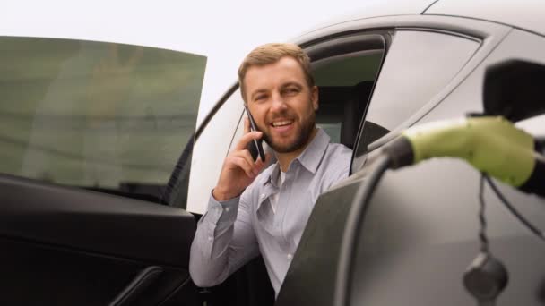 Muž Hovořící Telefonu Při Nabíjení Luxusního Elektromobilu Nabíjecí Stanici — Stock video