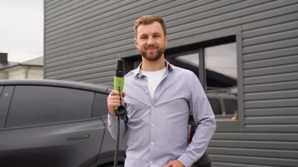 Porträt Eines Lächelnden Mannes Mit Ladegerät Einer Ladestation Für Elektroautos — Stockvideo
