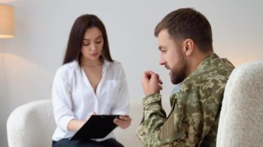 Psikolog üzgün erkek asker, Ptsd ile terapi oturumu sırasında notlar yapma.