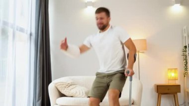 Kırık eli, ayağı ve koltuk değneği olan bir adam..