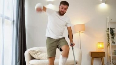 Kırık eli, ayağı ve koltuk değneği olan bir adam..