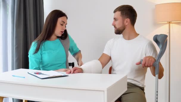 Female Doctor Bandaging Broken Hand Male Patient — Stock Video