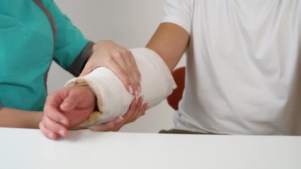 Nahaufnahme Einer Ärztin Die Gebrochene Hand Eines Männlichen Patienten Bandagiert — Stockvideo