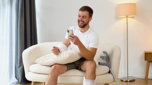 Člověk Zlomenou Rukou Nohou Dívá Vtipná Videa Smartphonu Rehabilitace Domu — Stock video