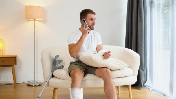 Человек Сломанной Рукой Ногой Веселится Разговаривая Телефону Друзьями Время Реабилитации — стоковое видео