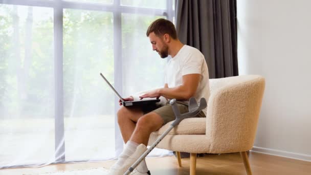 Niezdrowy Człowiek Freelancer Ranną Nogą Ramieniem Bandażu Siedzieć Kanapie Domu — Wideo stockowe